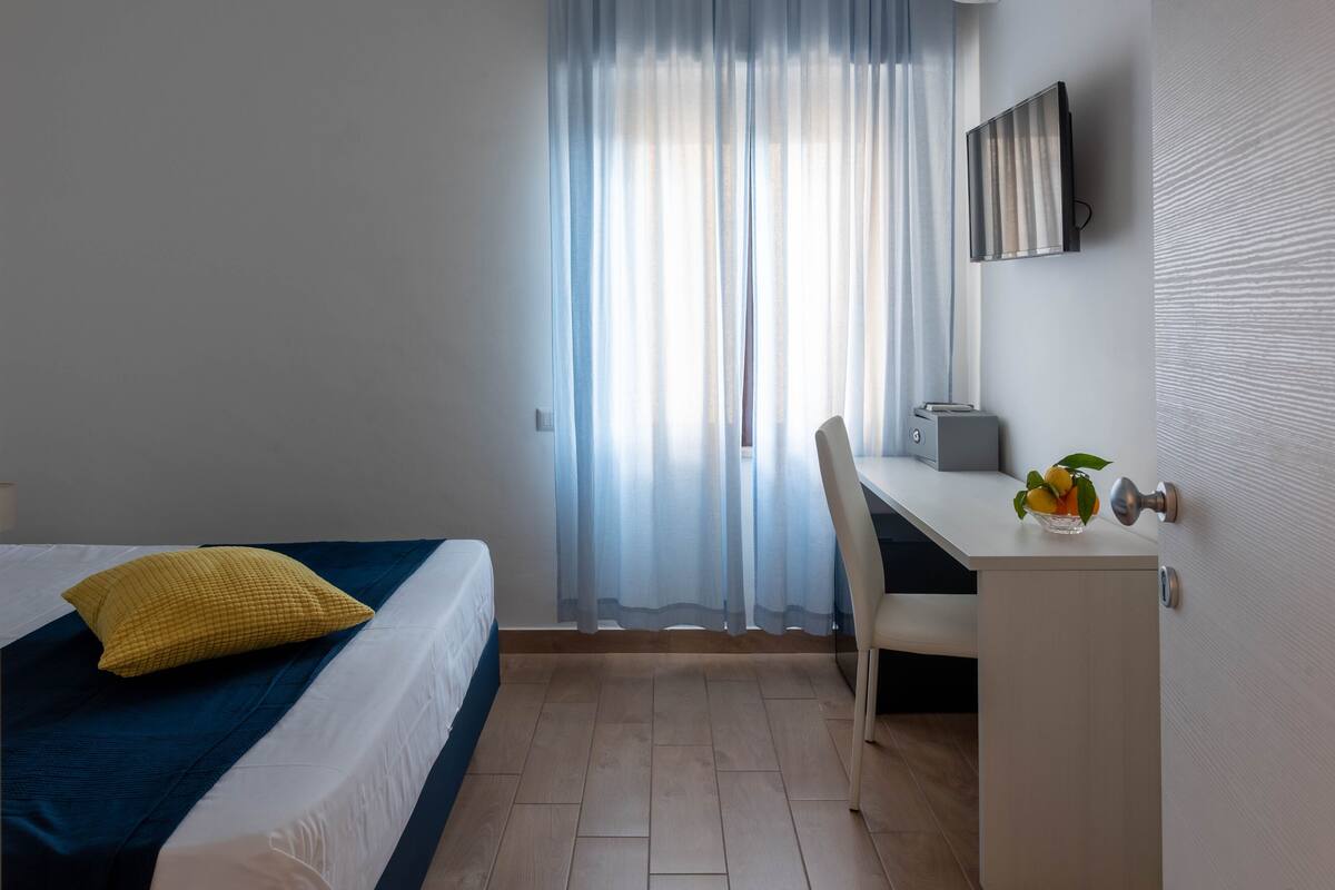 Une chambre d’hôtel avec un lit, un bureau et une chaise.