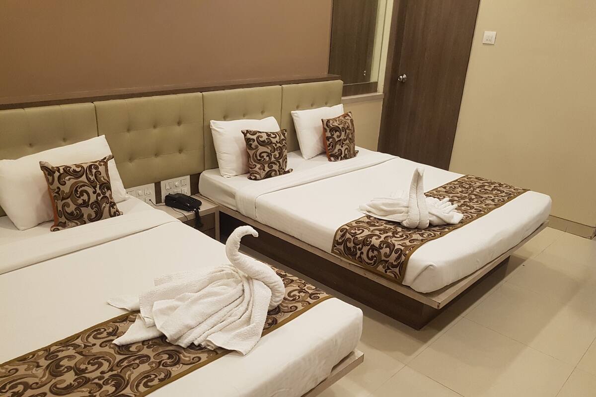 Two twin beds with white linens, patterned throw pillows, and a decorative towel on the bed.