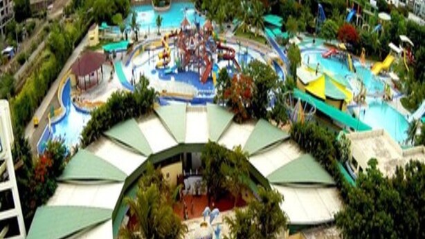 A water park with multiple slides and pools, surrounded by green umbrellas and trees. - Hotel Sai Chhatra (Rahata)