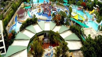 A water park with multiple slides and pools, surrounded by green umbrellas and trees.