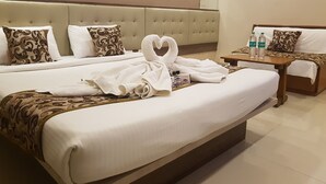 A hotel room with two beds, a bedside table with toiletries, and a heart-shaped towel on the bed. - Hotel Sai Chhatra (Rahata)