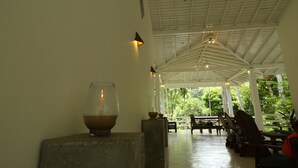 An indoor area with a high ceiling, a glass bowl with a candle, and wooden chairs and tables. - Beach Grove Villas (Unawatuna)