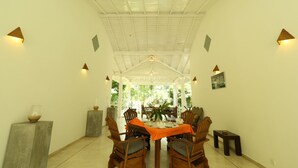 A dining area with a high ceiling, white walls, and a central table with chairs. - Beach Grove Villas (Unawatuna)