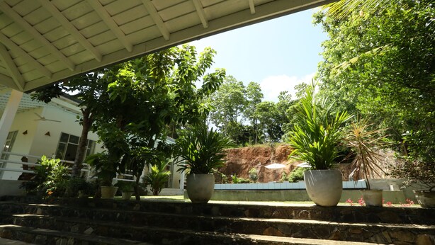 A covered outdoor area with stone steps leading up to a seating area with potted plants. - Beach Grove Villas (Unawatuna)