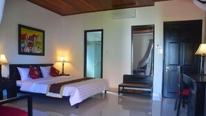 A hotel room with a bed, bedside lamps, a desk, a chair, a bench, a shower area, and a painting on the wall. - Hoi An Red Frangipani Villa (Da Nang)