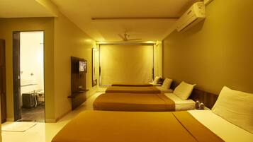 A hotel room with two beds, a ceiling fan, an air conditioning unit, and a bathroom visible through an open door.