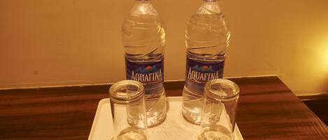 To Aquafina vandflasker og to tomme glas på et fad.