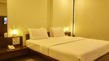 Une chambre d’hôtel équipée d’un lit, de lampes de chevet, d’un téléphone et d’un téléviseur fixé au mur.