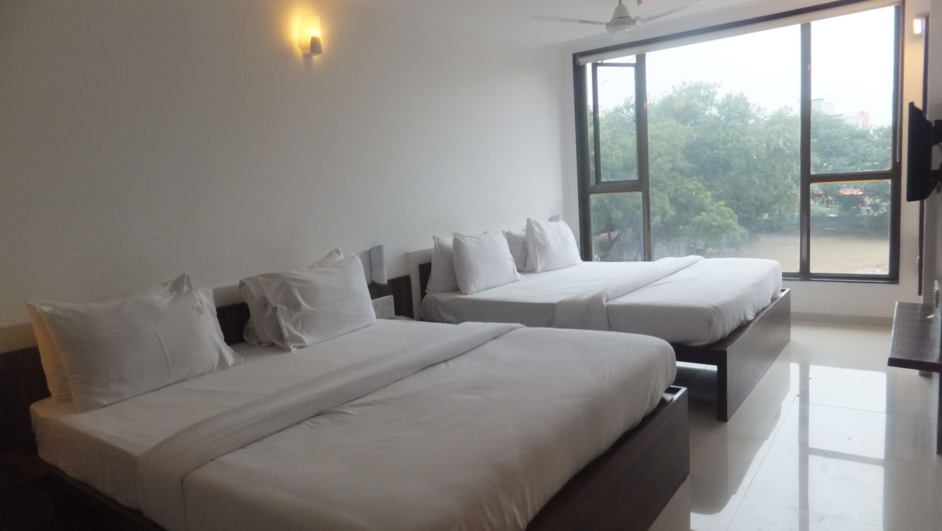 A hotel room with two beds, a large window, and a ceiling fan.