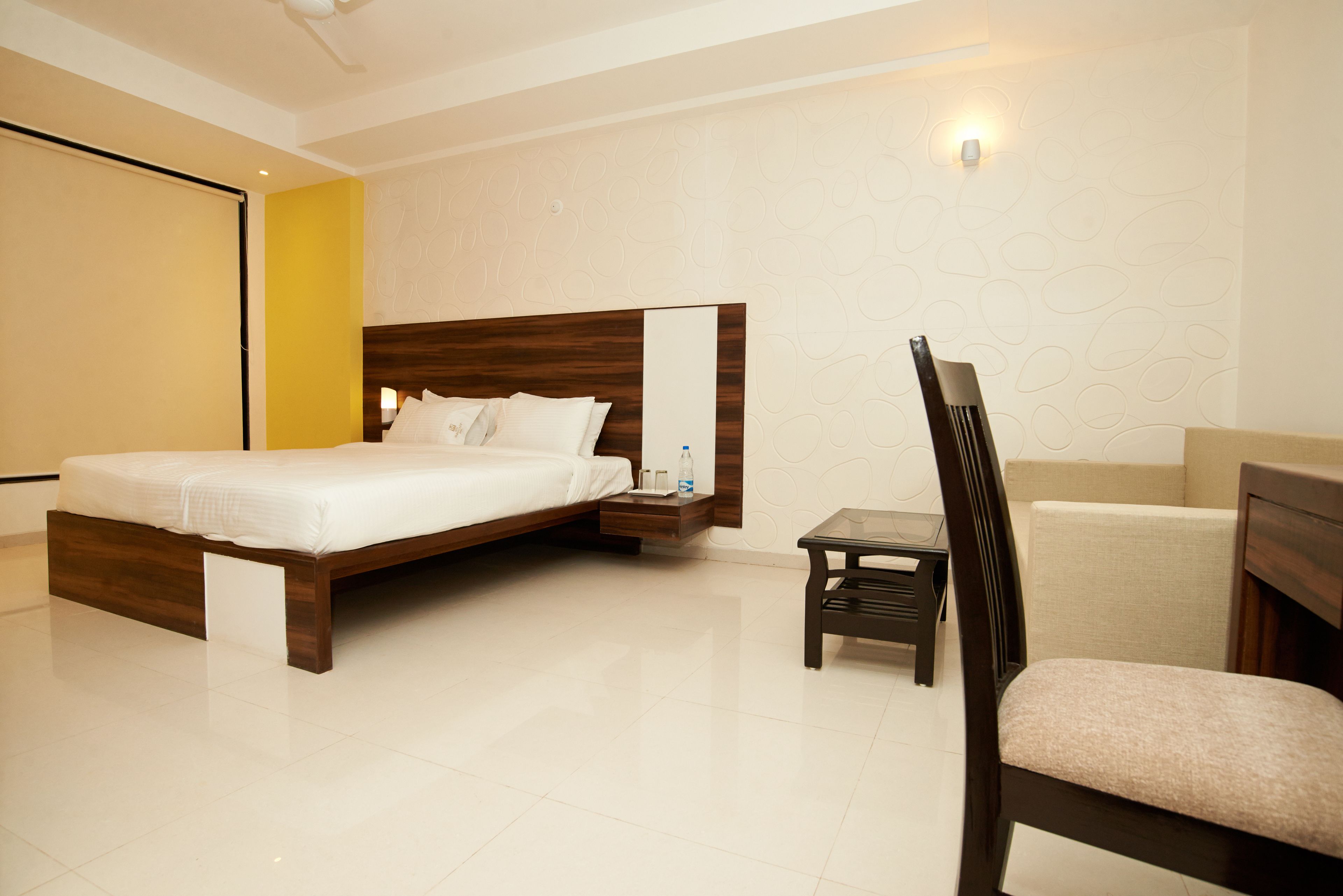 Una habitación de hotel moderna con una cama grande, una mesita de noche, una silla y una pequeña mesa.