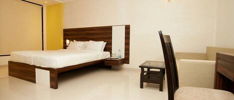 Una habitación de hotel moderna con una cama grande, una mesita de noche, una silla y una pequeña mesa.