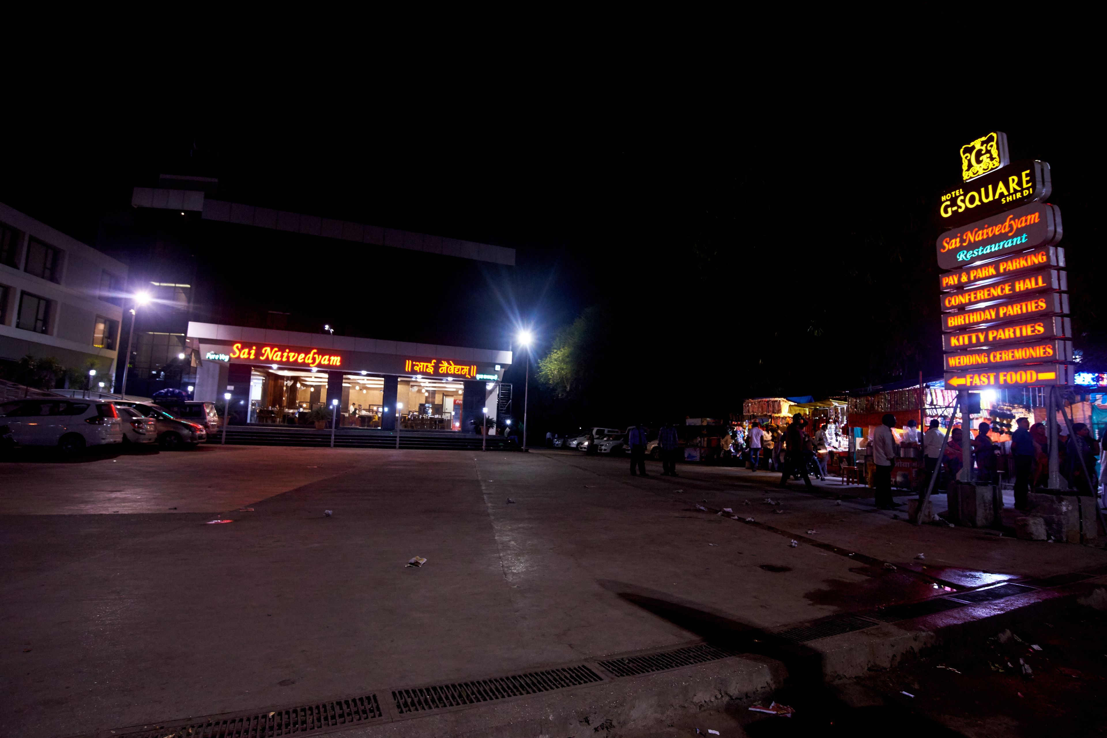 A hotel with a neon sign for 'Sai Naivedyam Restaurant' and 'G-Square' on the right.