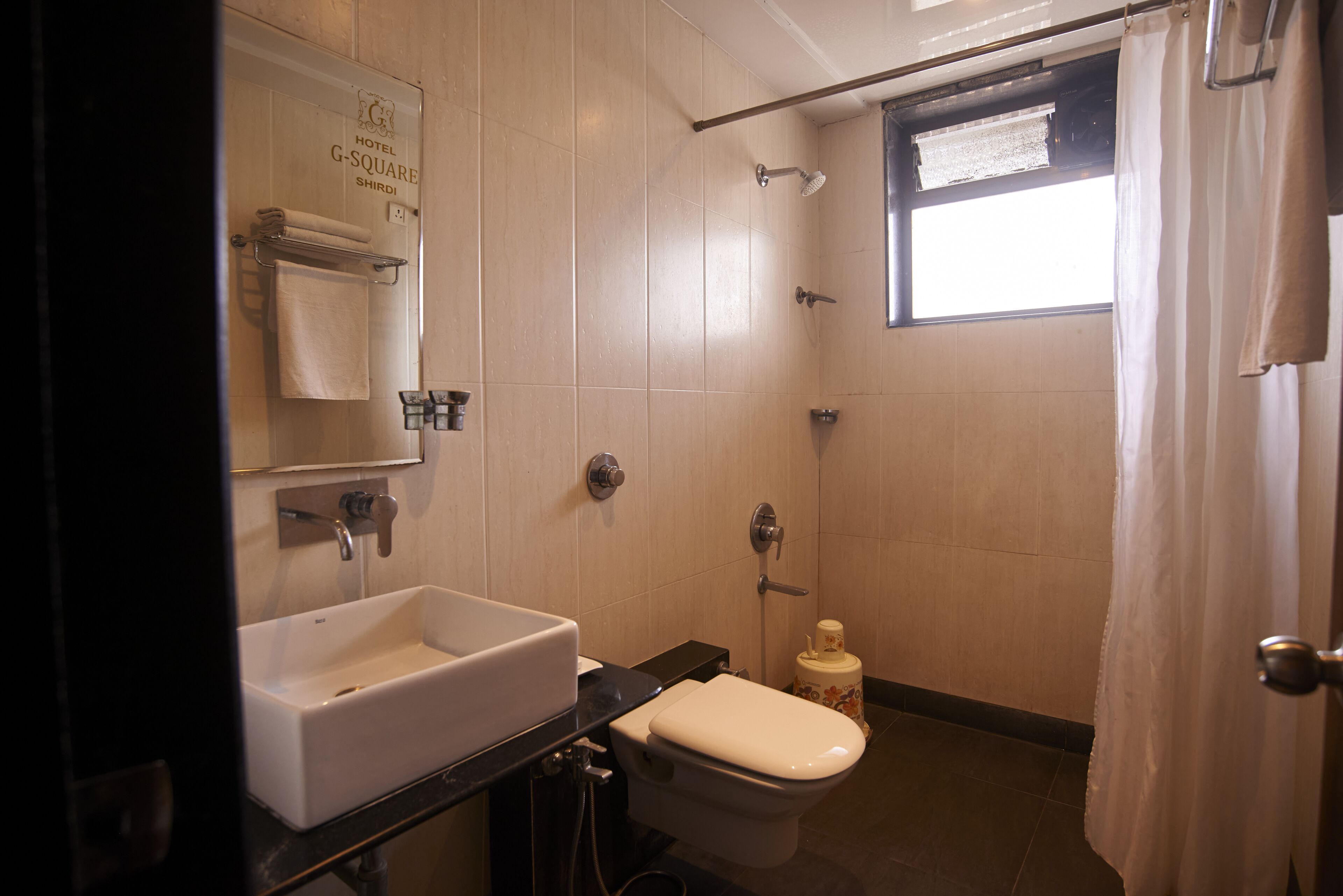 Baño de hotel con lavamanos, inodoro y ducha.