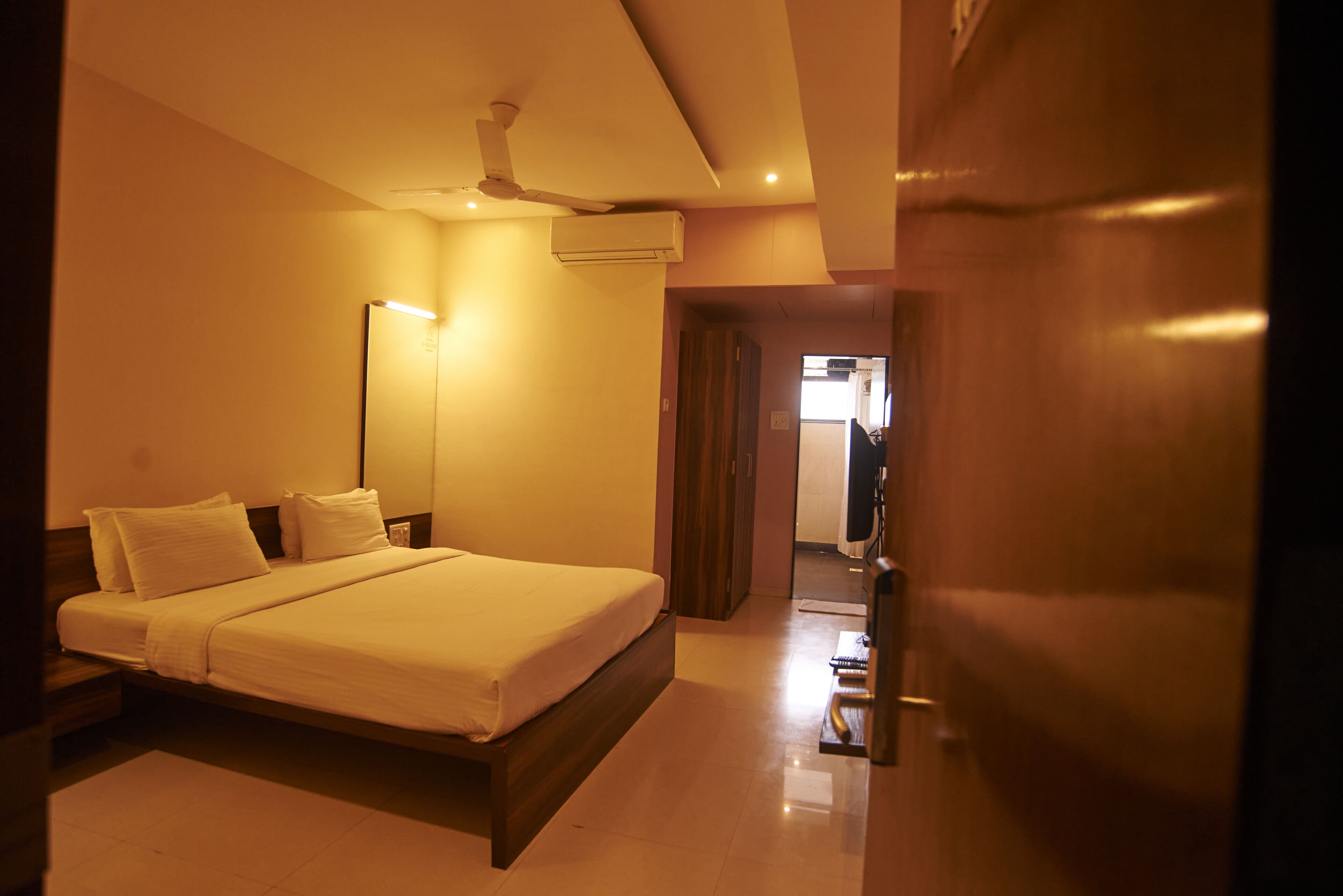 Una habitación de hotel con una cama grande, ventilador de techo y aire acondicionado.