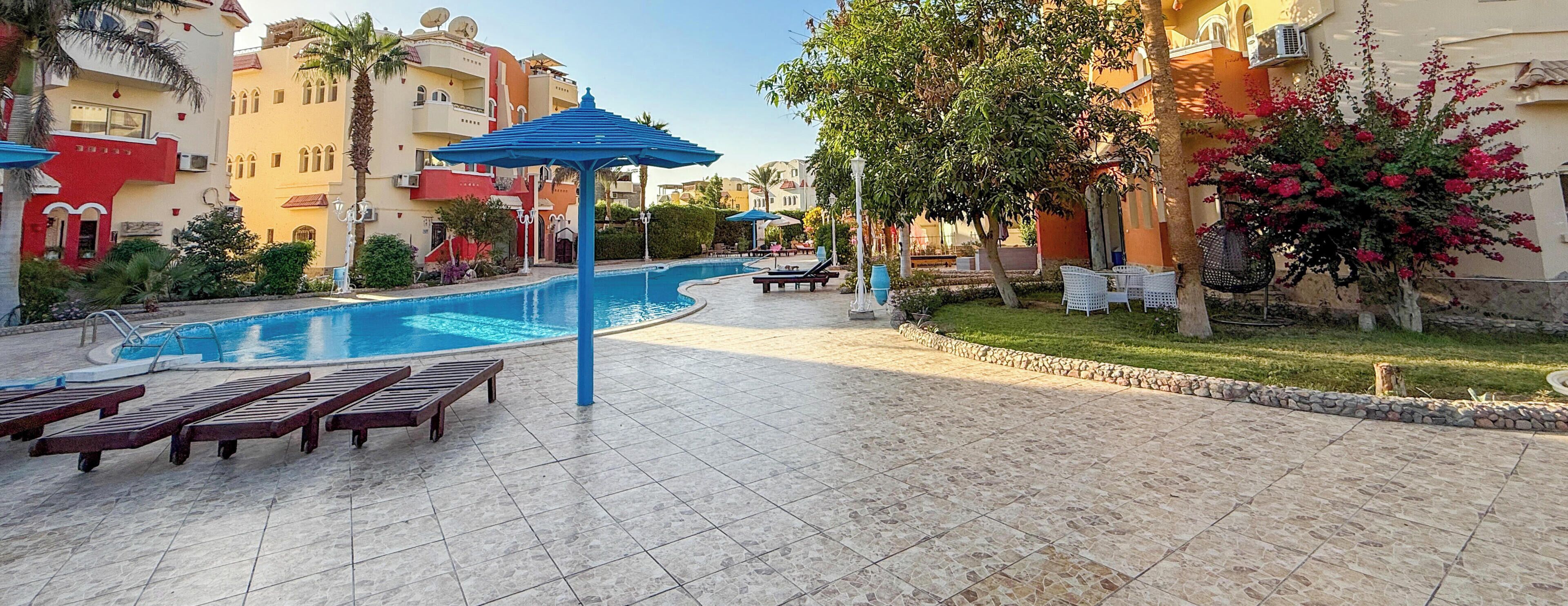 A swimming pool with lounge chairs, a gazebo, and a well-maintained garden with a tree and flowers.