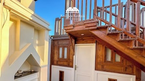 A wooden staircase leading to a white door with a small window, a tiled floor, and a stone structure to the left. - Green Garden Resort (Hurghada)