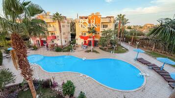 Ein Pool, umgeben von Palmen und einem Gebäude mit Balkonen.