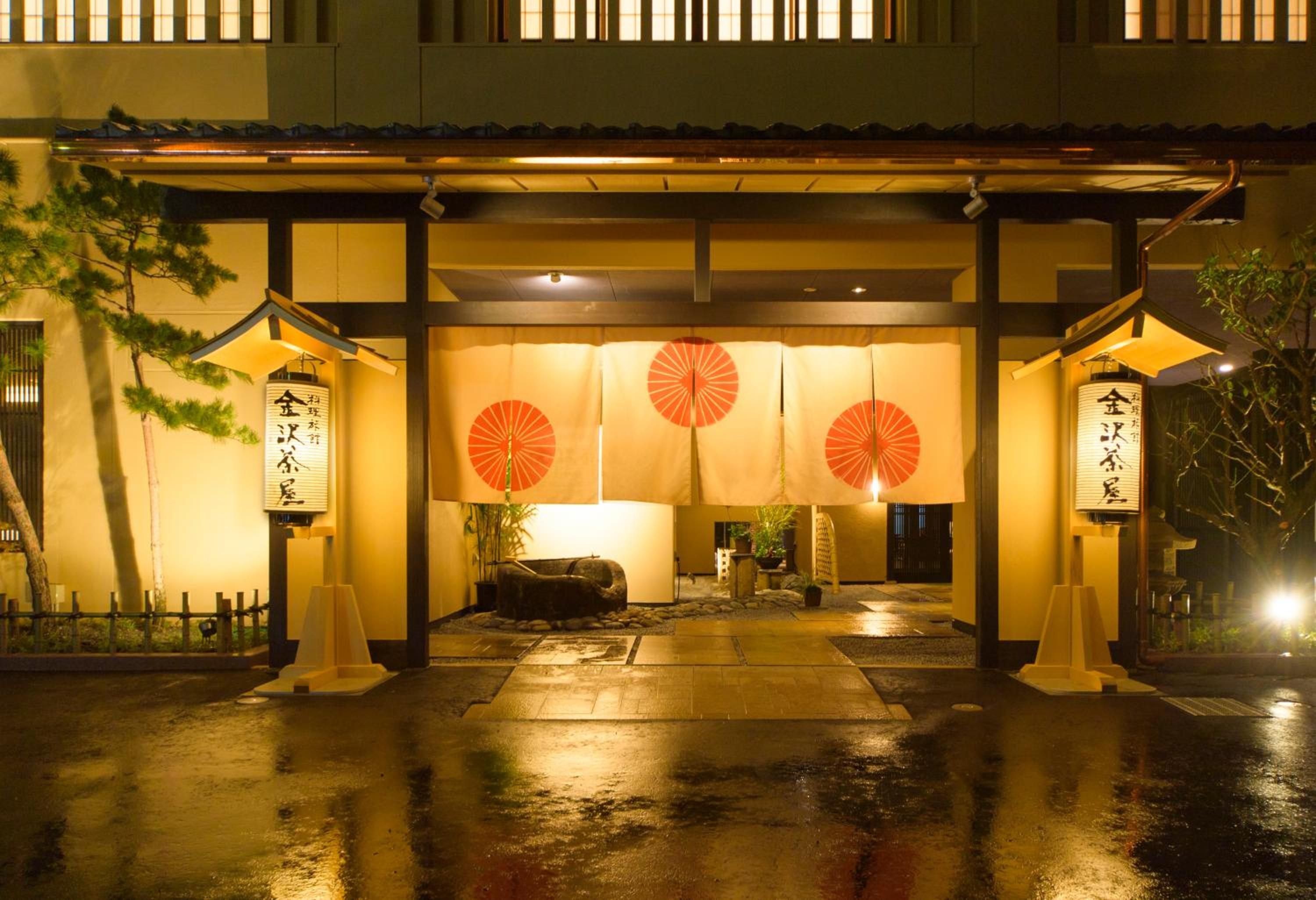 A traditional Japanese building entrance with a covered walkway, lanterns, and a stone lantern.