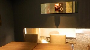 Un comedor con una mesa y sillas de madera, una obra de arte en la pared y una alfombra pequeña en el suelo.