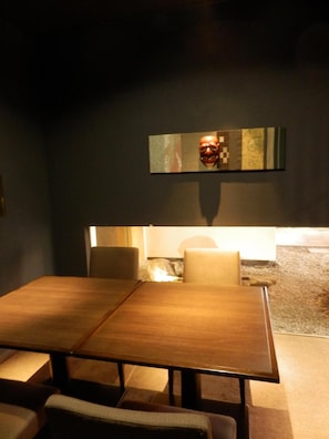A dining area with a wooden table and chairs, a wall-mounted artwork, and a small rug on the floor. - Kanazawa Chaya (Kanazawa)