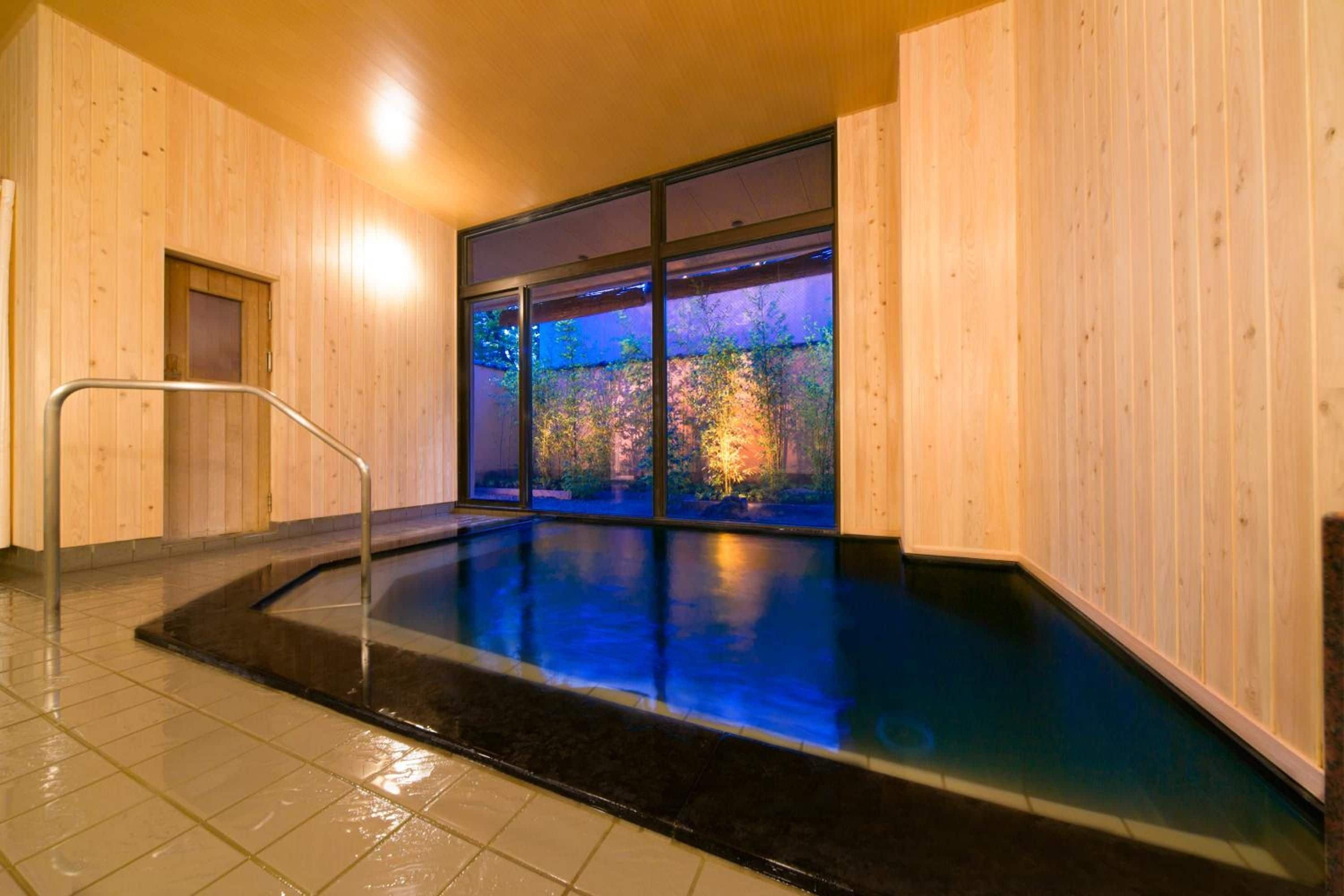 A spa room with a wooden interior, a glass wall, and a small pool.