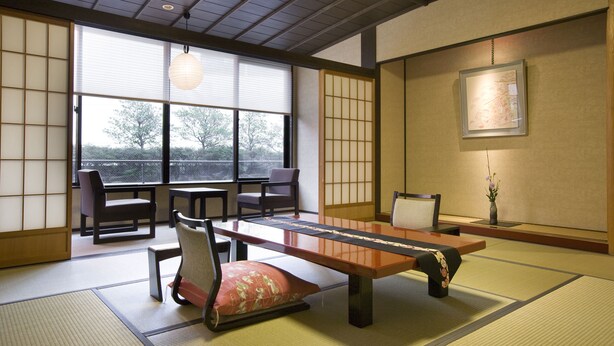 Une pièce de style japonais traditionnel, avec un sol recouvert de tatamis, une table basse et des portes coulissantes.