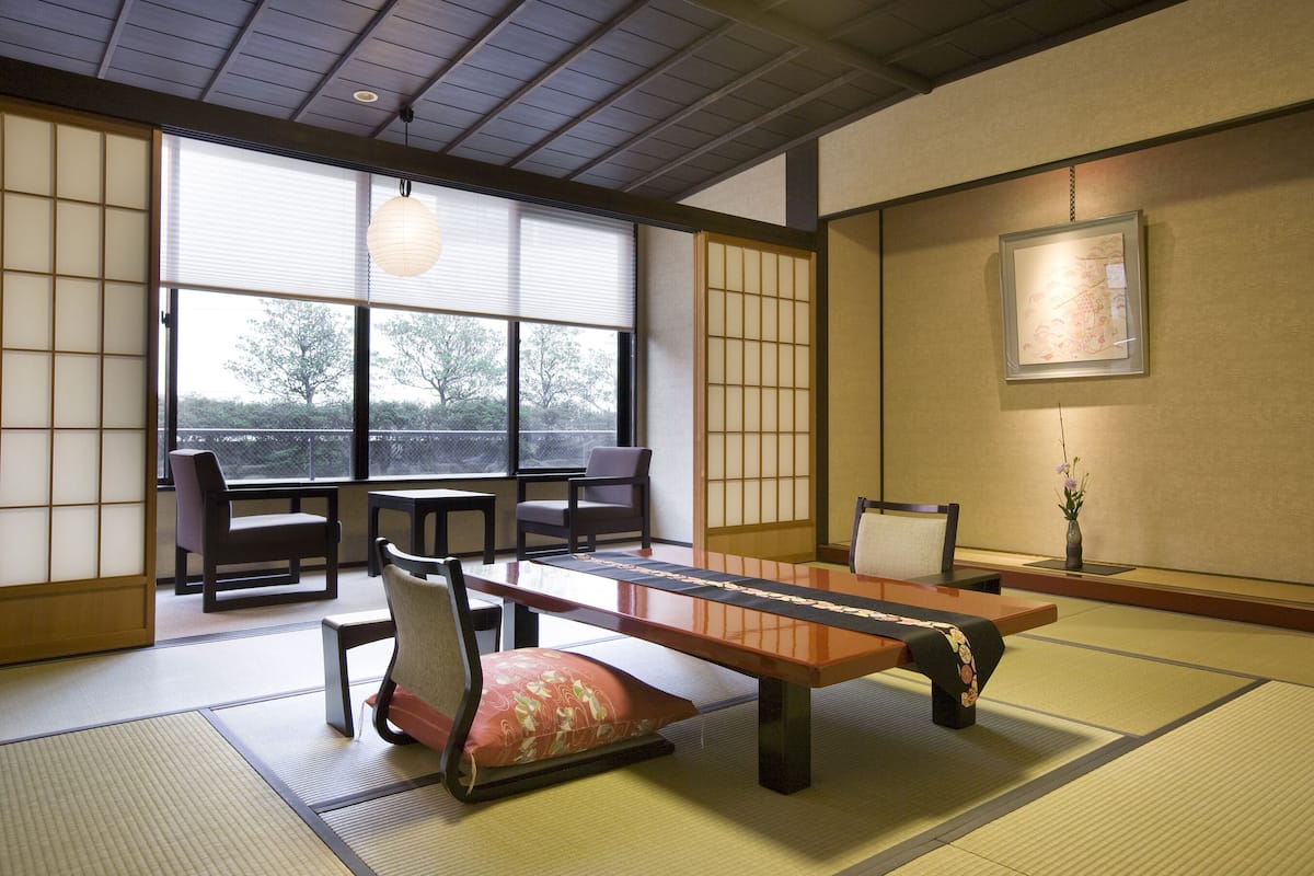 Ein traditioneller japanischer Raum mit Tatami-Böden, einem niedrigen Tisch und gleitenden Türen.