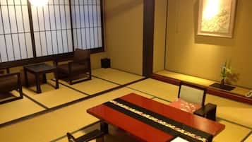 A traditional tatami mat room with a low table, chairs, and a sliding door.