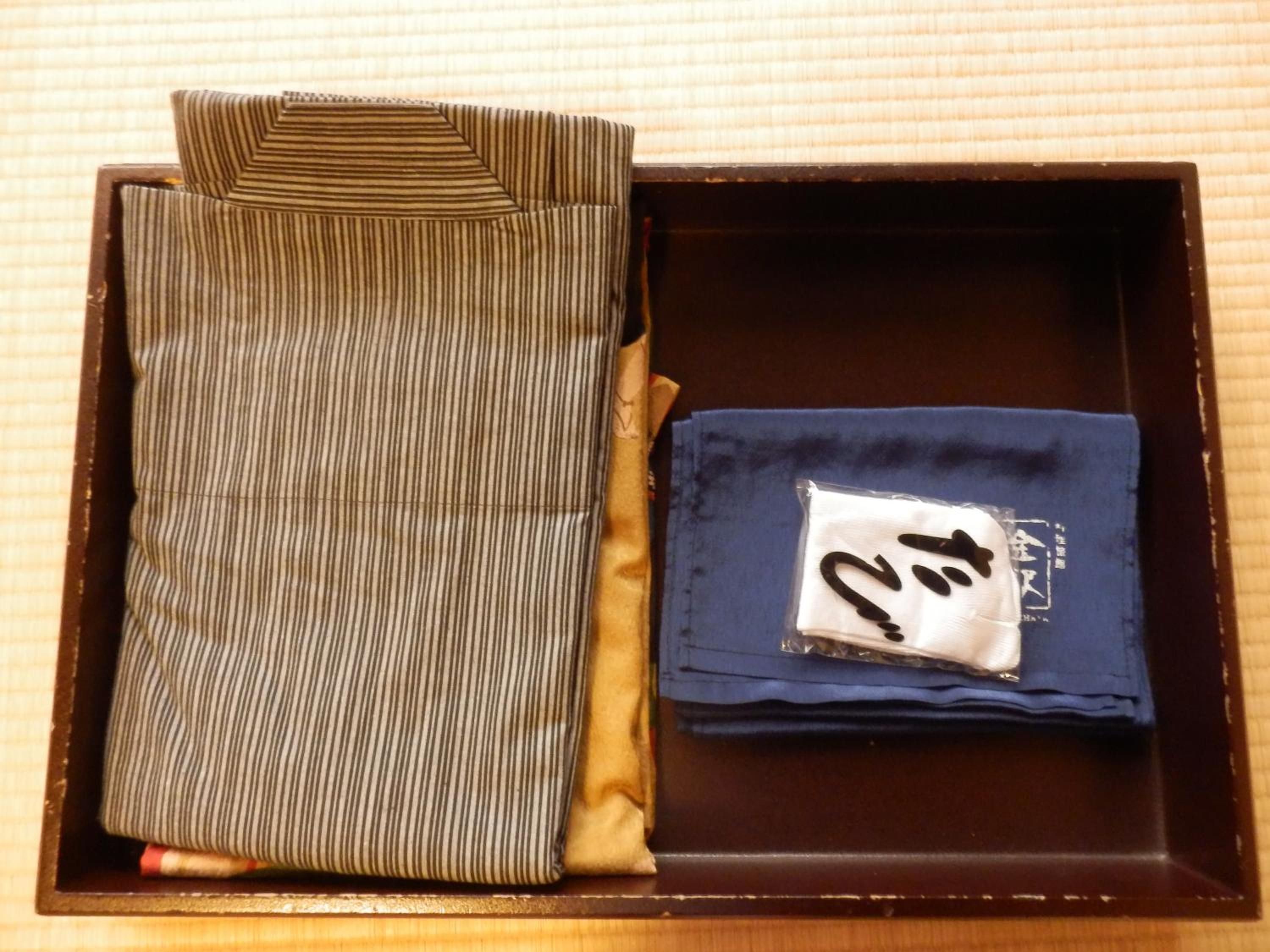 Una caja que contiene una camisa a rayas y una camisa azul doblada con una etiqueta blanca.