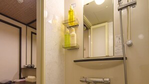 Une salle de bain équipée d’un lavabo, d’un miroir, d’une douche et d’une étagère où sont rangés les articles de toilette.