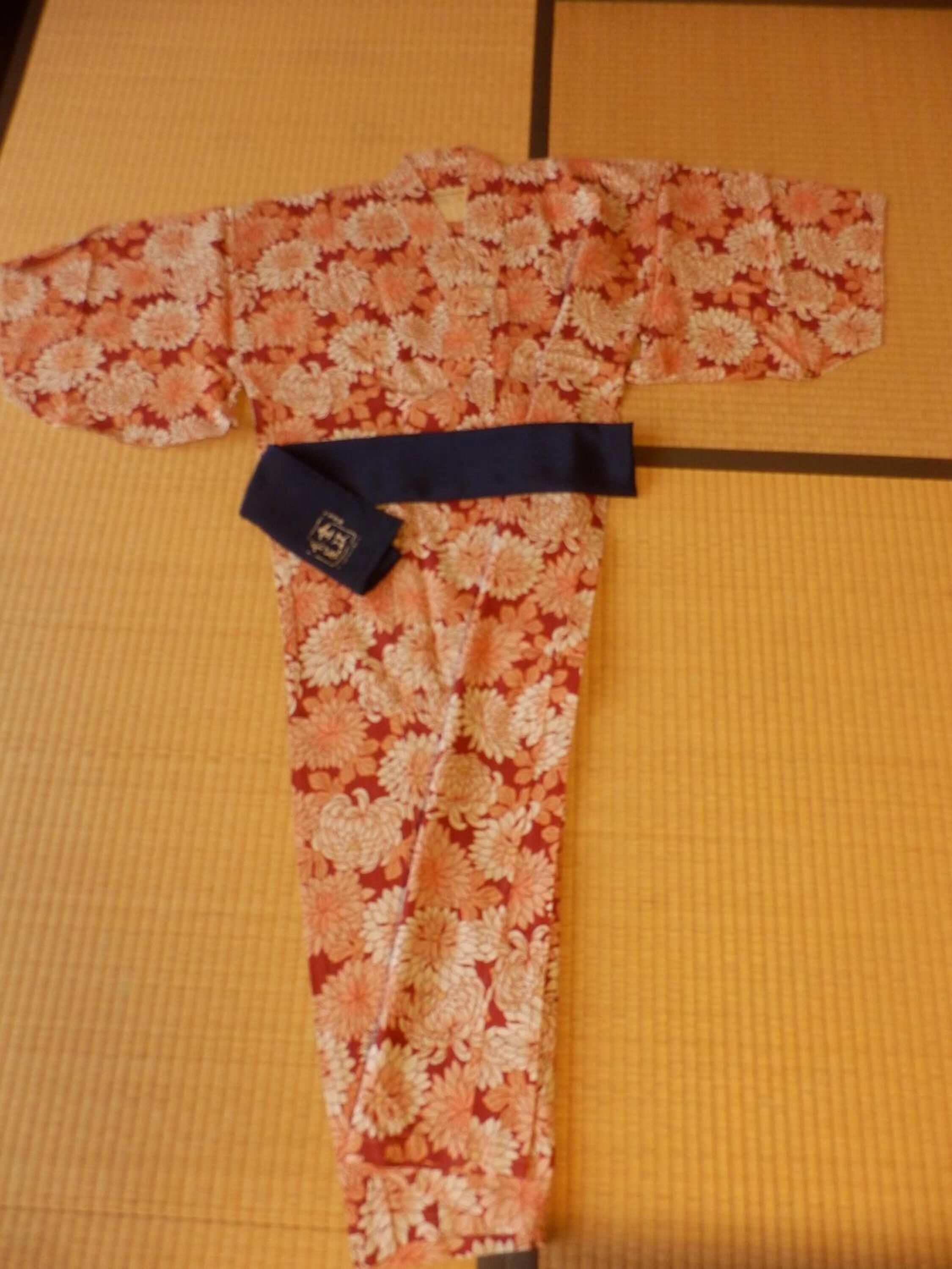 A traditional Japanese garment with a floral pattern laid out on a tatami mat.