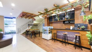 A modern coffee shop interior with a wooden counter, bar stools, and a chalkboard menu. - Hotel 88 Mangga Besar 62 by WH (Jakarta)
