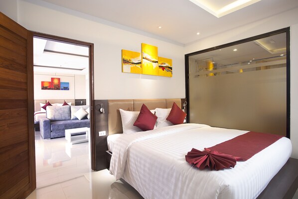 Una habitación de hotel moderna con una cama grande, suelo de madera, un sofá y una pared decorada con obras de arte.