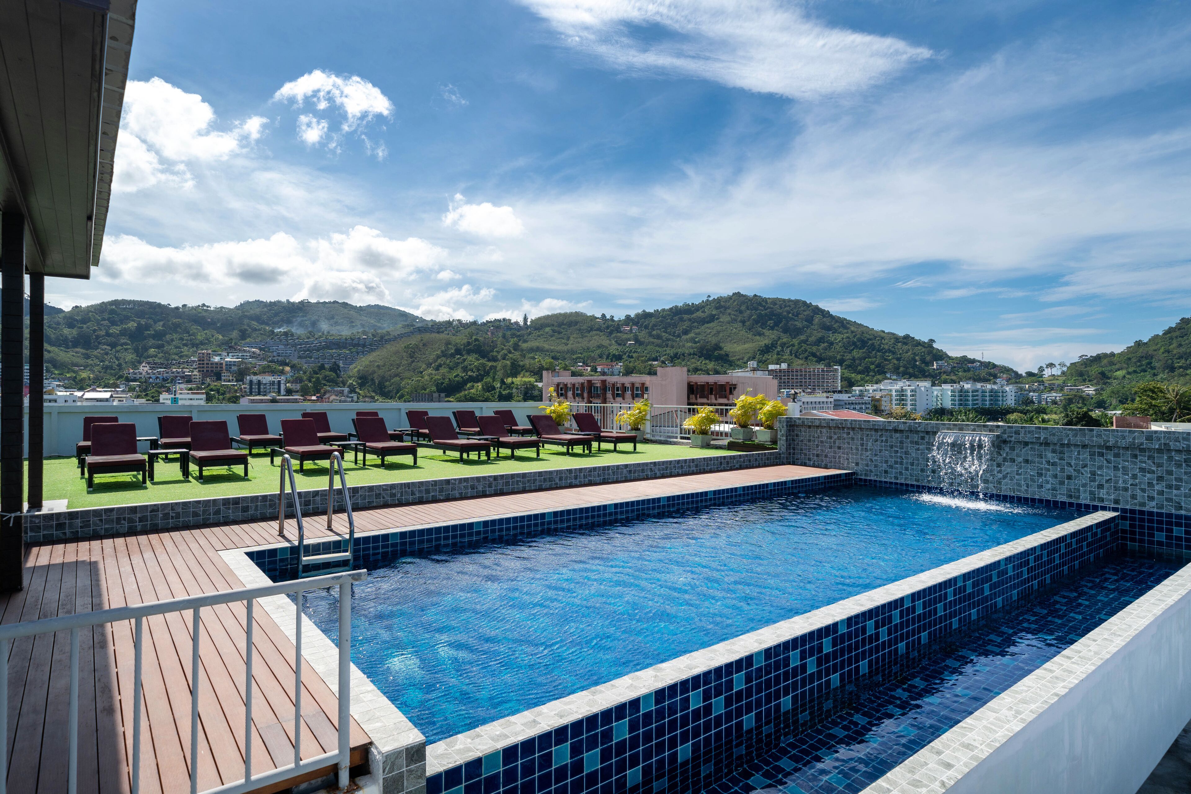 A rooftop swimming pool with a view of a mountainous landscape.