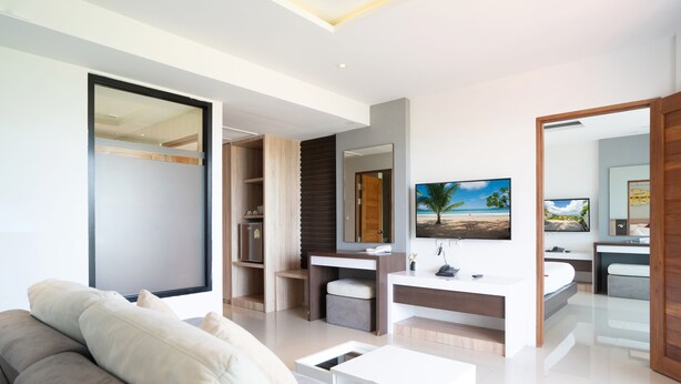 Una sala de estar moderna con sofá, mesa de centro, televisor y baño con lavabo y espejo.