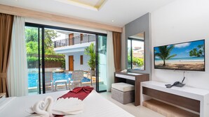 Habitación de hotel con cama, escritorio, televisión y vistas a una piscina y balcón.