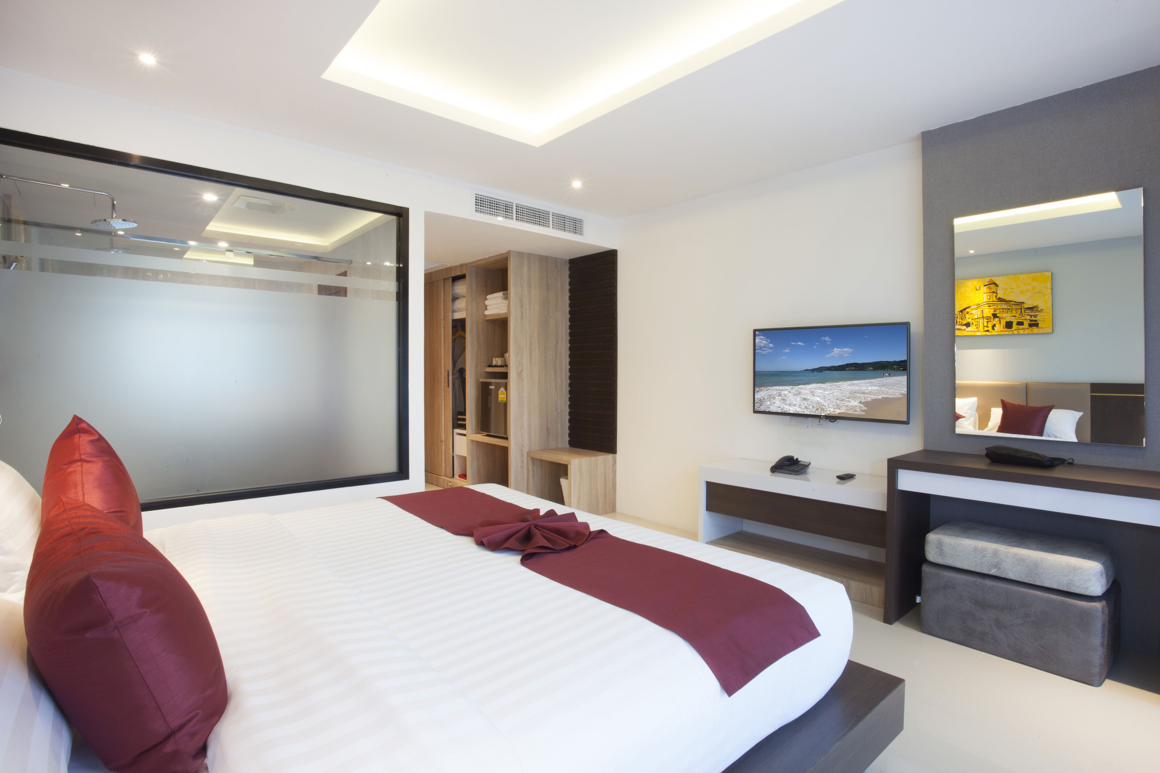 Une chambre d’hôtel moderne dotée d’un grand lit, d’une télévision, d’un bureau et d’un dressing.
