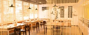 Un restaurant avec de longues tables, des lampes suspendues et une grande fenêtre offrant une belle vue.