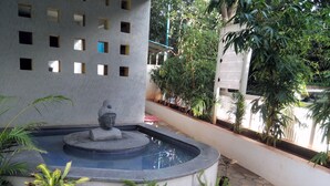 Un patio con una fuente, plantas en macetas y una estatua de Buda.