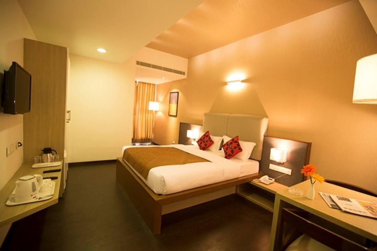 Une chambre d’hôtel équipée d’un lit, d’une table de chevet, d’une lampe et d’un téléviseur fixé au mur.
