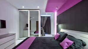 Un dormitorio moderno con una cama grande, un armario, un espejo y un televisor.