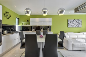 Une cuisine moderne avec des meubles blancs, une table à manger avec des chaises et un canapé blanc.