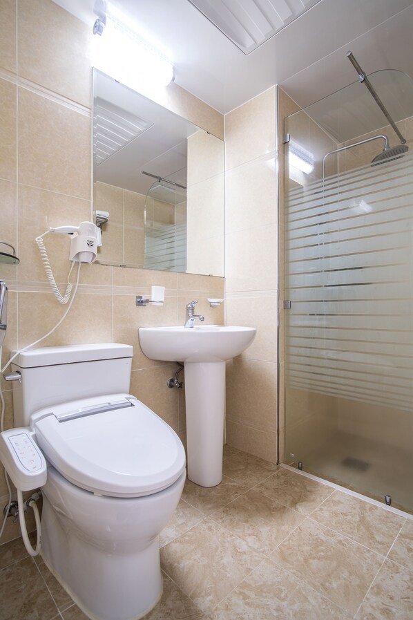 A bathroom with a toilet, sink, and glass shower enclosure.