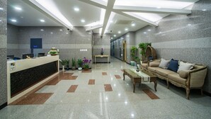 Un área de recepción moderna con un mostrador, un sofá y plantas en macetas.