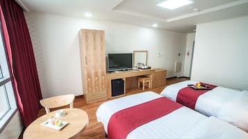 Ein Hotelzimmer mit zwei Betten, einem Schreibtisch, einem Fernseher und einem kleinen Tisch mit einer Essschale.
