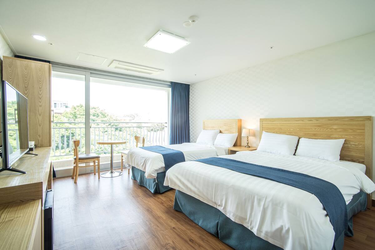 Ein Hotelzimmer mit zwei Betten, einem Schreibtisch und einem Balkon mit Blick.