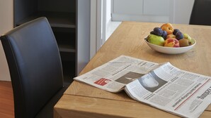 A dining area with a table, chairs, a bowl of fruit, and a television on the wall. - Congress Apartments by Hotel du Commerce (Basel)