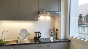 A modern kitchen with a stainless steel kettle, a dish rack, and a coffee maker on the counter. - Congress Apartments by Hotel du Commerce (Basel)