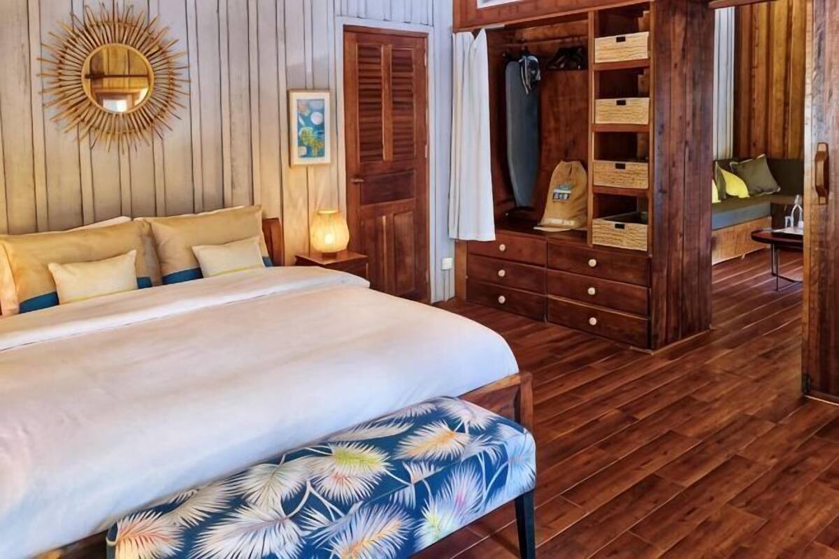 Un dormitorio con cama, armario de madera y un banco.