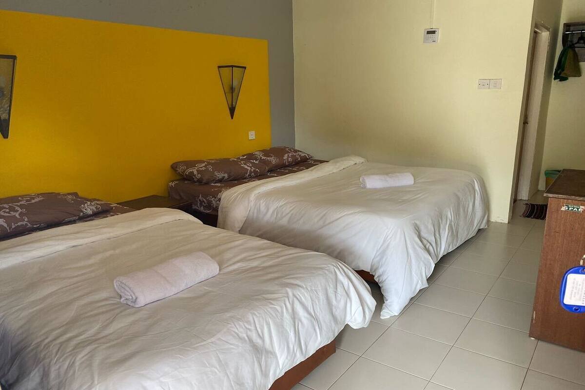 A hotel room with two beds, each with a pillow and a rolled towel.